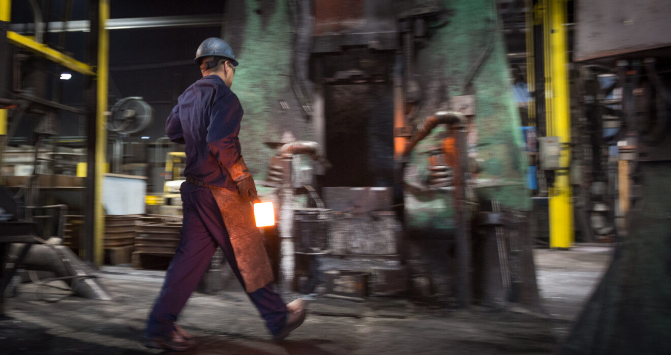 worker carrying hot billet towards hammer